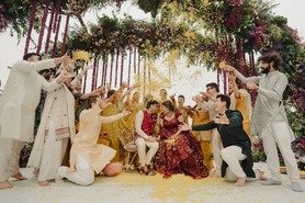 Bride and groom receiving blessings from family under a floral arch