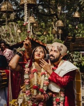 Bride and groom looking up at a floral shower during the varmala ceremony