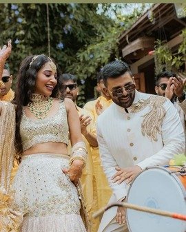 Bride and groom dancing to the dhol in mehendi outfits