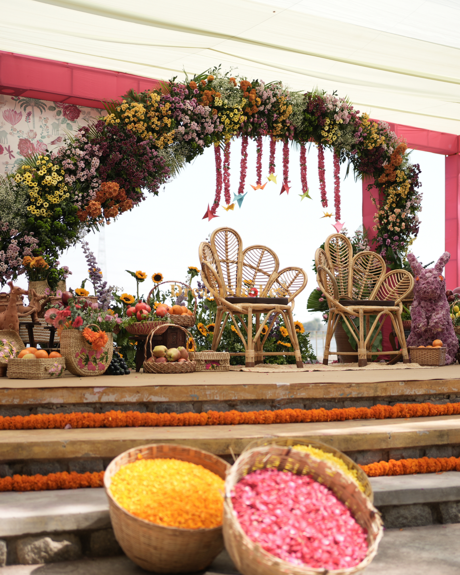 Elegant outdoor garden wedding ceremony with floral aisle décor, white sofas, gold chairs and hanging lights
